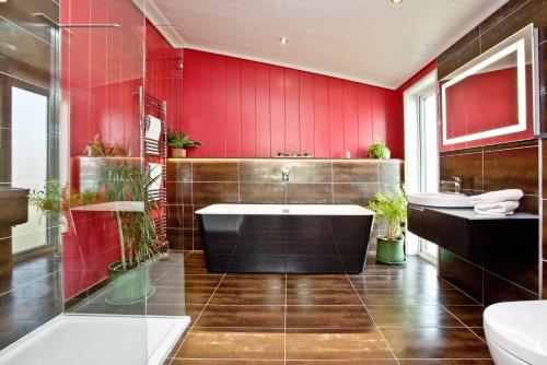 a bathroom with red walls and a tub and a sink at Pomegranate, Strawberryfield Park in Cheddar