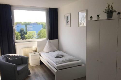 ein Schlafzimmer mit einem Bett, einem Stuhl und einem Fenster in der Unterkunft Komplett ausgestattetes Apartment in Dormagen in Dormagen