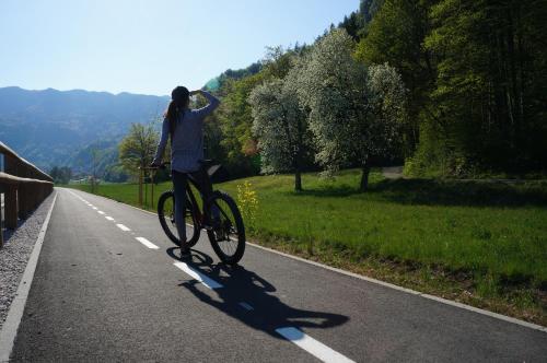 Una donna che va in bicicletta lungo la strada di Rooms Ravnik a Bled
