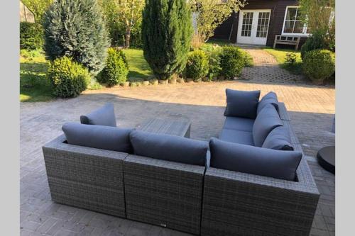 a brown couch with blue pillows on a patio at Gartenvilla@Baltic-Chalets in Warnkenhagen
