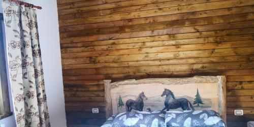 a wooden wall with two horses on top of a bed at Cabana Agroturistica Runc in Borşa