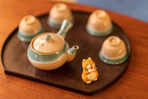 a small figurine of a cat next to a teapot at TABITABI STAY HIGASHIYAMA in Kyoto