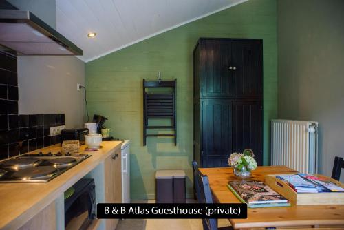 a kitchen with green walls and a wooden counter top at Atlas Private Guesthouse in Bruges