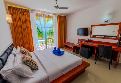 a bedroom with a bed and a desk and a television at Athiri Beach Maldives in Dhigurah