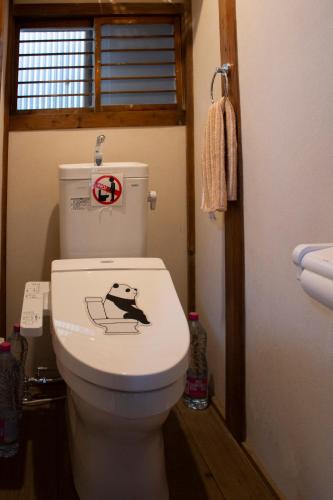 a bathroom with a toilet with a dog sticker on it at Guest Cafe Kuchikumano in Kamitondacho