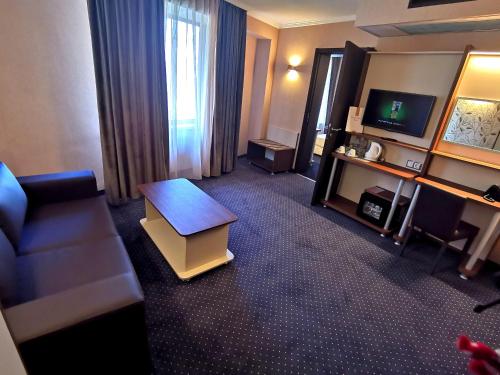 a hotel room with a couch and a television at Elate Plaza Hotel in Sofia