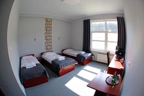 a hotel room with two beds and a desk and a window at Hotel Centrum in Bydgoszcz