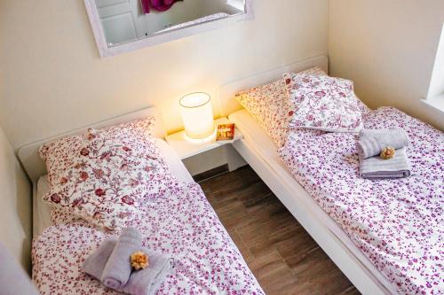 2 Betten in einem kleinen Schlafzimmer mit einer Lampe und Kissen in der Unterkunft Waldhaus Emma in Suderburg