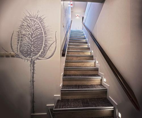 a stairway with a painting of a plant on the wall at Piccolo Panzió Vendéglő Vinoteca in Zalaegerszeg