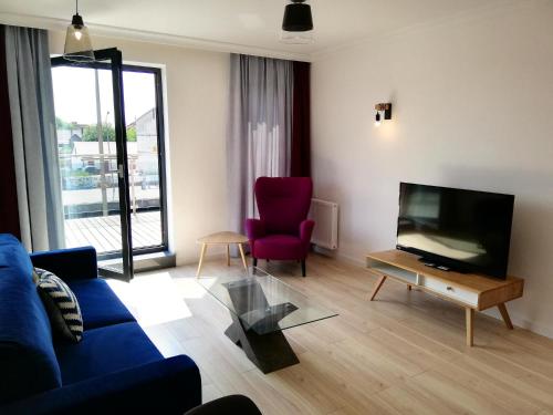 salon z niebieską kanapą i telewizorem w obiekcie Apartamenty Kropla Bałtyku w mieście Darłowo