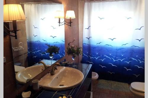 baño con lavabo y ventana con pájaros en la cortina en Casa Playa los Percheles, en Puerto de Mazarrón