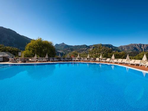 una grande piscina con sedie e montagne sullo sfondo di Hotel Fuerte Grazalema a Grazalema