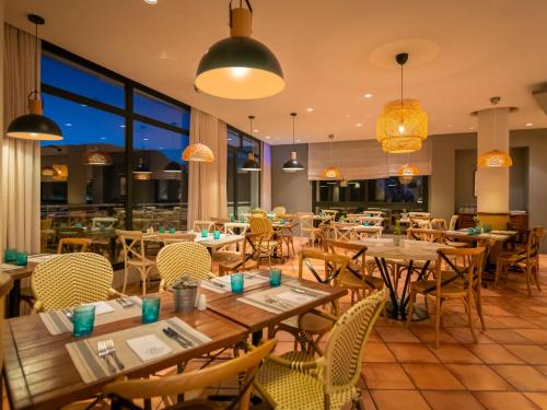 een restaurant met houten tafels en stoelen en ramen bij Hotel Fuerte Grazalema in Grazalema