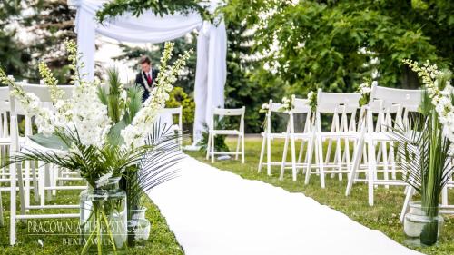 a row of white chairs and a aisle with flowers at Hotel & Restauracja Timberland in Orzesze