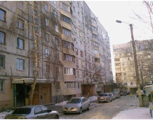 a street with cars parked in front of a building at Уютная квартира рядом с метpo Холодная гора in Kharkiv