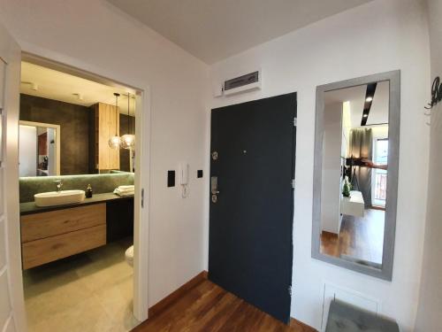 a bathroom with a black door and a sink at Nowy Apartament 58 z klimatyzacją in Iława