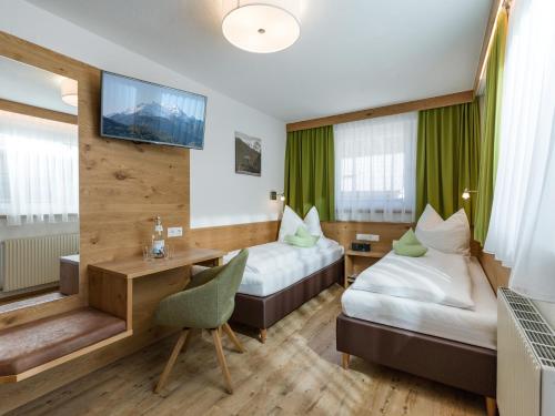 a hotel room with two beds and a desk at Apartmenthaus Katharina in Mayrhofen