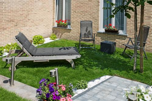 a garden with a couch and two chairs and flowers at Parkhotel Gent Centrum in Ghent
