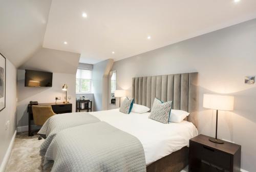 a hotel room with two beds and a desk at Gorse Hill Hotel in Woking