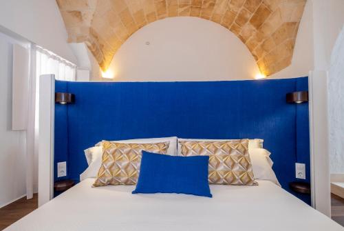 a bed with a blue headboard and two pillows at Divina Suites Hotel Singular -Adults Only in Ciutadella