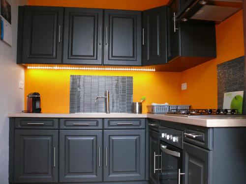 een keuken met zwarte kasten en een oranje muur bij Gîte La Malavisée in Leernes