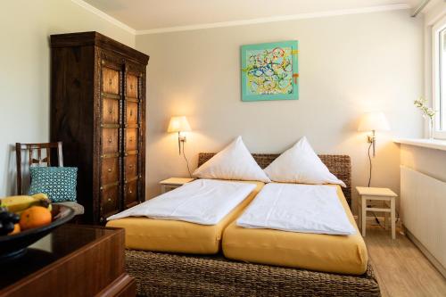 - une chambre dotée d'un lit avec des draps blancs dans l'établissement Landhaus Calluna, à Undeloh