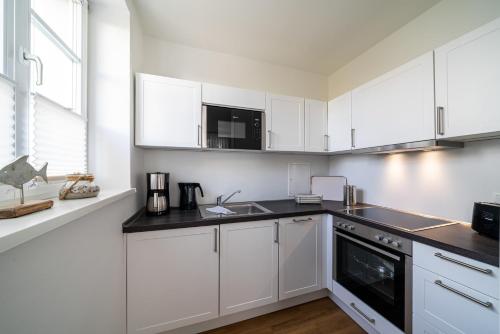 a white kitchen with white cabinets and a sink at Haus Heidelberg in Göhren