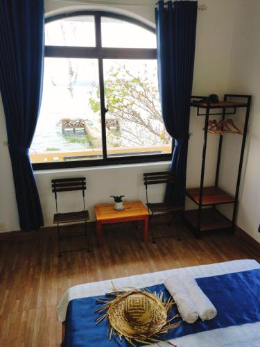 a bedroom with a large window with blue curtains at Sunbay Homestay Cu Lao Cham in Tân Hiệp