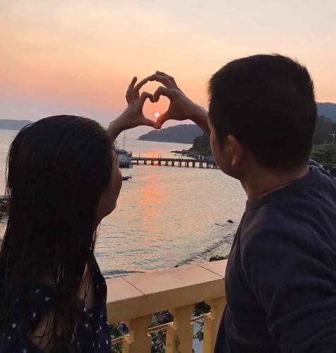 a man and a woman making a heart with their hands at Sunbay Homestay Cu Lao Cham in Tân Hiệp