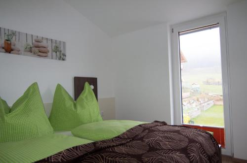 Un dormitorio con una cama con almohadas verdes y una ventana en Ferienwohnung bei der Steinbergbahn en Leogang
