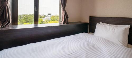 a bedroom with a large white bed with a window at Okazaki New Grand Hotel in Okazaki