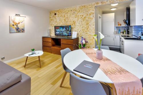 a living room with a kitchen and a table with a laptop on it at JessApart– Babka Tower Apartment in Warsaw