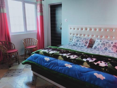 1 Schlafzimmer mit einem Bett und 2 Stühlen in der Unterkunft Vamoose Pahadi Ghar in Kanatal