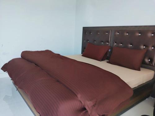 a bed with red pillows and a brown blanket at Vamoose Pahadi Ghar in Kanatal