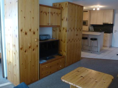 a kitchen with wooden cabinets and a tv and a table at Chesa Gravas in Lenzerheide
