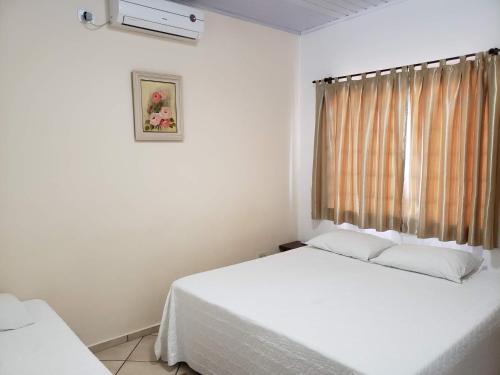 Un dormitorio blanco con dos camas y una ventana. en Angel Family Houses, en Foz do Iguaçu