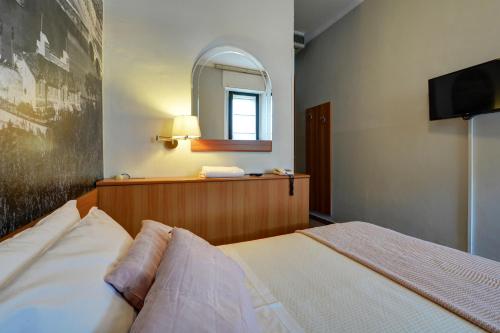 a bedroom with a bed and a mirror and a television at Astor Hotel in Turin