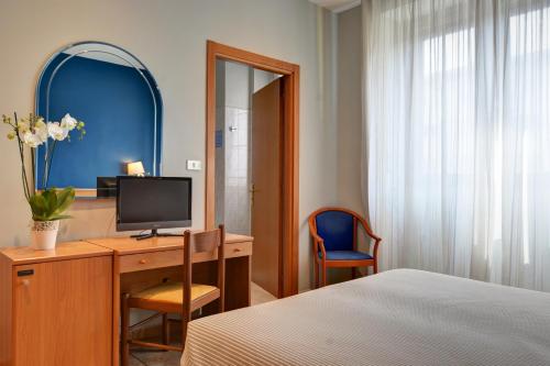 a bedroom with a desk with a tv and a bed at Astor Hotel in Turin