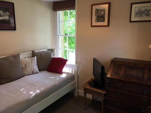 a bedroom with a bed and a tv and a window at Green Cottage, on Langcliffe village green in Settle