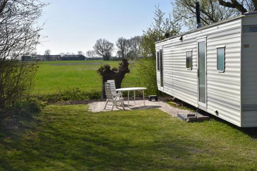 a table and chairs next to a trailer at Camping De Blauwe Reiger in Pieterzijl