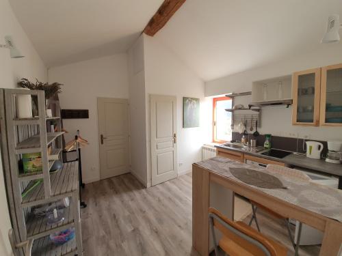 une cuisine avec une table et un comptoir dans l'établissement Le Colombier d'Amalthée, à Vernay