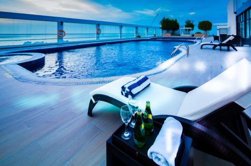 a pool with a table with wine bottles and glasses at Nordic Palace and spa in Manama