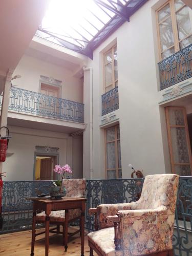 een kamer met 2 stoelen en een tafel met bloemen erop bij HOTEL MARCEILLAC in Castelsarrasin