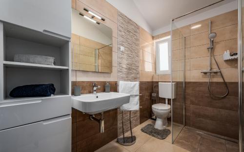 a bathroom with a sink and a toilet and a shower at Apartments Nelle in Pula