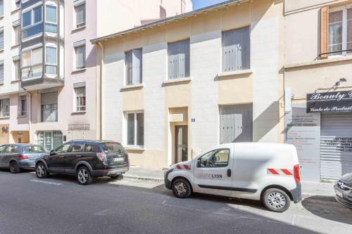two cars parked on a street in front of a building at Le Cocon Villette in Lyon