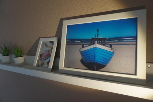 a shelf with two pictures and a blue boat on it at Ferienunterkünfte Zwischen Meer & See in Bansin