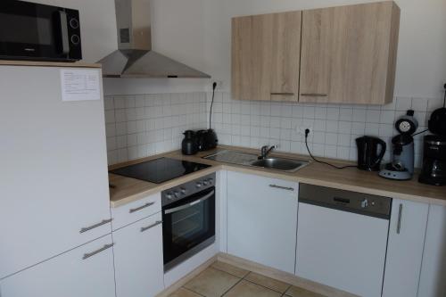 a small kitchen with white cabinets and a sink at Ferienwohnungen Viersen in Viersen
