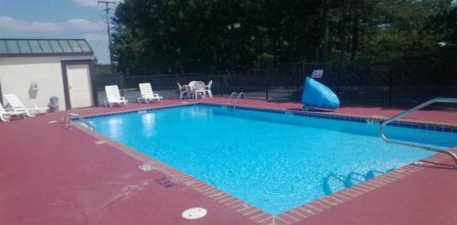 Una gran piscina azul con sillas y una mesa. en Baymont by Wyndham Caddo Valley/Arkadelphia en Arkadelphia