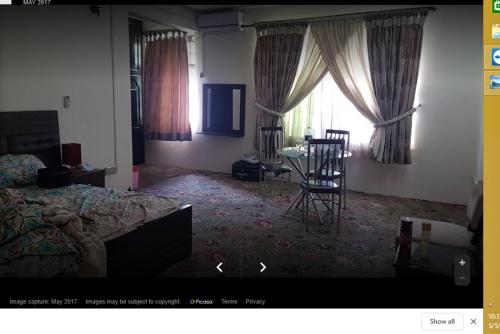 uma sala de estar com uma cama, uma mesa e cadeiras em Gilgit Deosai Executive Guest House em Gilgit