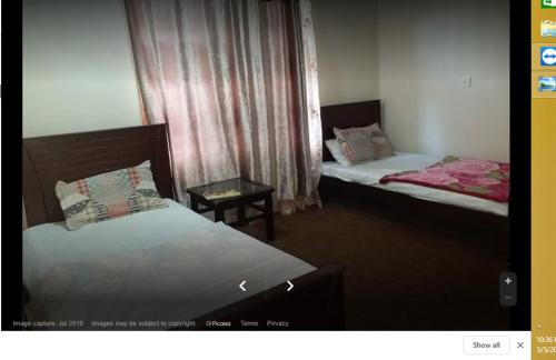 a room with two beds and a table in it at Gilgit Deosai Executive Guest House in Gilgit